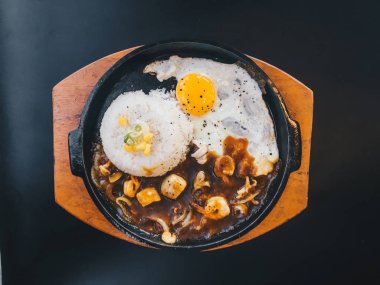 Güneşli kızarmış yumurta ve Izgara Et veya garnitür mısır ve pırasa yakın çekim siyah arka plan üzerinde izole sıcak tabak ile sığır eti ile Pirinç