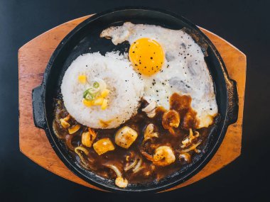 Güneşli kızarmış yumurta ve Izgara Et veya garnitür mısır ve pırasa yakın çekim siyah arka plan üzerinde izole sıcak tabak ile sığır eti ile Pirinç