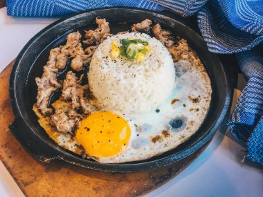 Pilav Güneşli kızarmış yumurta ve Izgara Et veya garnitür mısır ve pırasa yakın çekim ahşap masada sıcak tabakta sığır eti