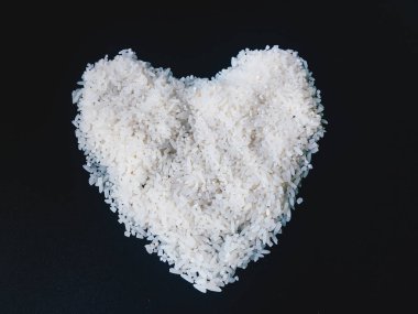 Endonezya ham pirinç siyah arka plan üzerinde izole merkezinde insan kalp şekli gibi bir görünüm ile. Sağlıklı pirinç işareti veya sembolleri