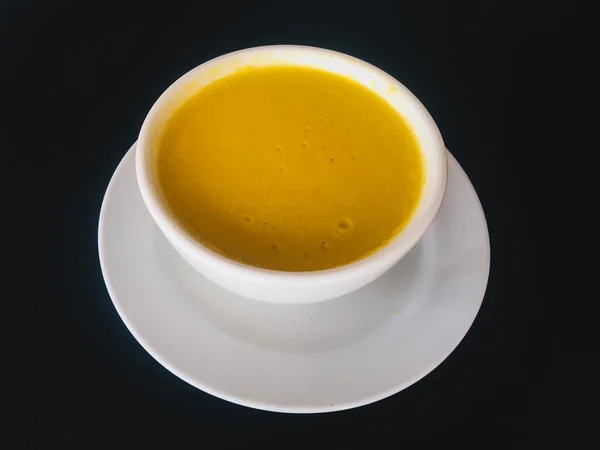 Pure yellow creamy Corn soup with in a white bowl isolated on black background. Healthy food. Top view
