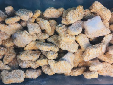 stack of raw frozen chicken nuggets in a cooler in the supermarket clipart