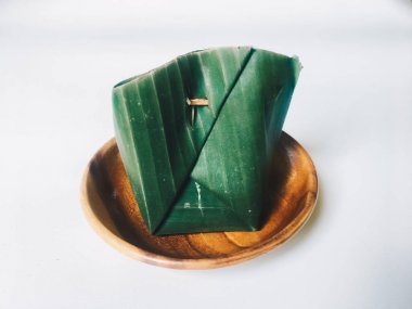 Bant Ketan Endonezya geleneksel gıda muz sarılmış yemeye hazır yaprakları. yapışkan pirinç fermantasyonu. Endonezya geleneksel gıda. Ahşap plaka üzerinde beyaz bir arka plan karşı izole