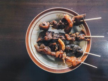 Sate Kambing Goreng veya keçi satay geleneksel Endonezya gıda koyun eti biber ve fıstık sosu ile ahşap masada dilimlenmiş arpacık ile karışık yapılır