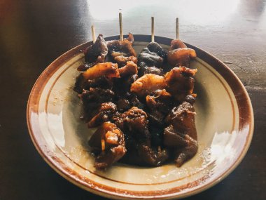 Sate Kambing Goreng veya keçi satay geleneksel Endonezya gıda koyun eti biber ve fıstık sosu ile ahşap masada dilimlenmiş arpacık ile karışık yapılır