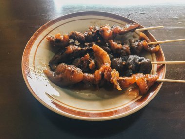 Sate Kambing Goreng veya keçi satay geleneksel Endonezya gıda koyun eti biber ve fıstık sosu ile ahşap masada dilimlenmiş arpacık ile karışık yapılır