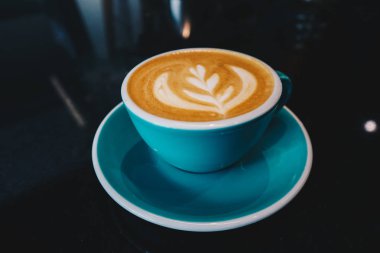 Kahve Latte veya Cappuccino köpüklü bir fincan, kafede siyah masada yeşil kahve fincanı