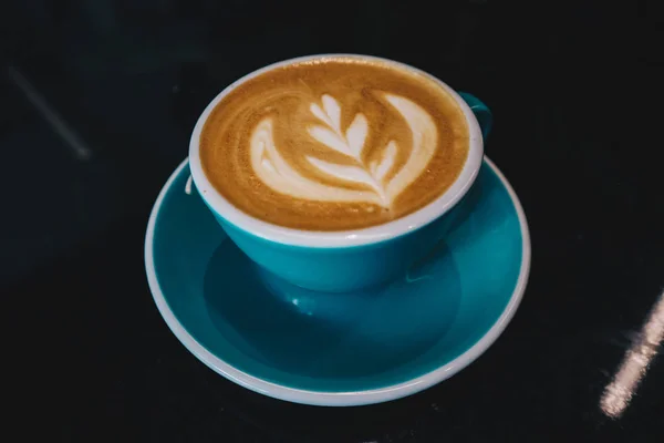 Kahve Latte veya Cappuccino köpüklü bir fincan, kafede siyah masada yeşil kahve fincanı