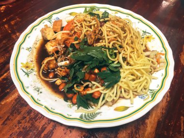 Ahşap masada kasede servis edilen sebze ve deniz ürünleri ile Asya yemeği.