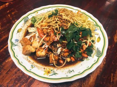 Ahşap masada kasede servis edilen sebze ve deniz ürünleri ile Asya yemeği.