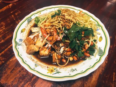 Ahşap masada kasede servis edilen sebze ve deniz ürünleri ile Asya yemeği.