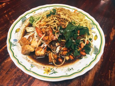 Ahşap masada kasede servis edilen sebze ve deniz ürünleri ile Asya yemeği.