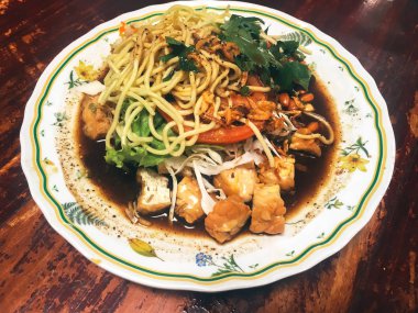 Ahşap masada kasede servis edilen sebze ve deniz ürünleri ile Asya yemeği.