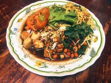 Ahşap masada kasede servis edilen sebze ve deniz ürünleri ile Asya yemeği.