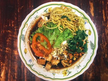 Ahşap masada kasede servis edilen sebze ve deniz ürünleri ile Asya yemeği.