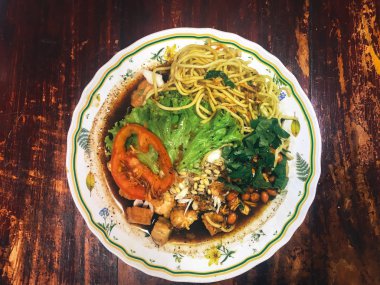 Ahşap masada kasede servis edilen sebze ve deniz ürünleri ile Asya yemeği.