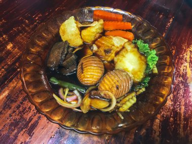 Ahşap masada kasede servis edilen sebze ve deniz ürünleri ile Asya yemeği.