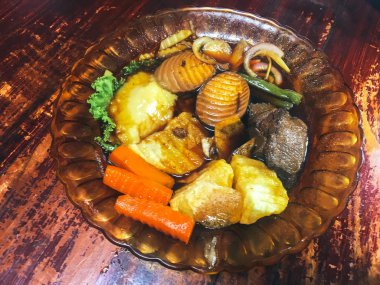 Ahşap masada kasede servis edilen sebze ve deniz ürünleri ile Asya yemeği.