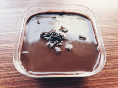 Ahşap masa üzerinde plastik kapta çikolatalı dondurma