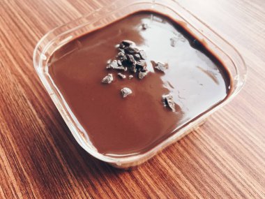 Ahşap masa üzerinde plastik kapta çikolatalı dondurma