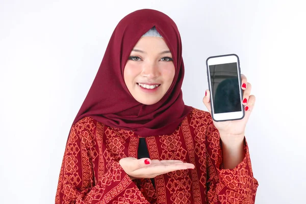 Молода Жінка Азіатського Ісламу Посміхається Вказуючи Смартфон Стоїть Білому Фоні — стокове фото