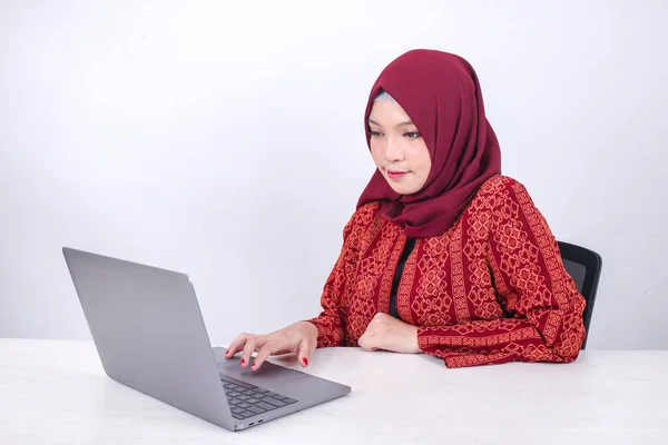 年轻的亚洲伊斯兰女性在白色背景的笔记本电脑上工作时 正坐在那里享受着微笑 — 图库照片