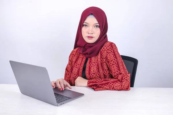 年轻的亚洲伊斯兰女性正坐在笔记本电脑上认真地看着摄像机孤立的白色背景 — 图库照片