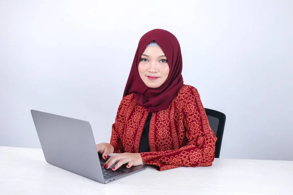 Young Asian Islam woman is sitting enjoy and smiling when working on laptop on white background.