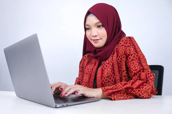若いアジアのイスラム教徒の女性は 白い背景にラップトップで作業するときに楽しさと笑顔に座っている — ストック写真