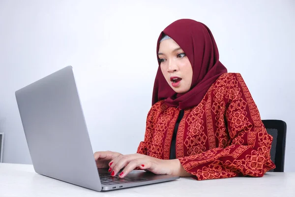 Young Asian Islam woman is shock when holding and working on laptop computer isolated white background