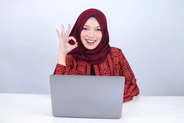 若いアジアのイスラム教徒の女性は Okの手のサインとラップトップで作業するときに笑顔と幸せ — ストック写真