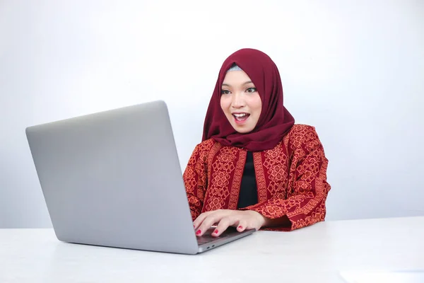 スカーフを被った若いアジア系イスラム教徒の女性はショックを受け テーブルの上のラップトップで見たものに興奮しています — ストック写真