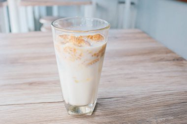 Tahta masadaki bir bardak sütün içinde gevrek yulaflı bisküviler.