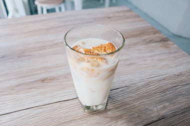 Tahta masadaki bir bardak sütün içinde gevrek yulaflı bisküviler.