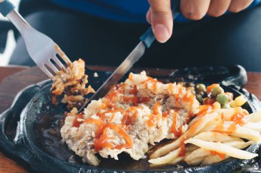 Bir el, ızgara soslu ve patatesli tavuk buğulama tabağı kesti.