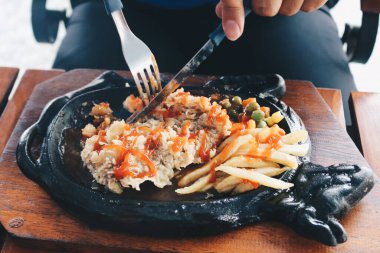 Bir el, ızgara soslu ve patatesli tavuk buğulama tabağı kesti.