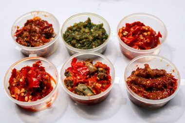 Aneka Sambal Endonezya. Beş çeşit Endonezya baharatlı baharat tabağı mini kâse içinde. Yakınlarda bir sepet taze biber var..