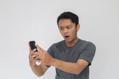 Asyalı adamın, gri arka planda akıllı telefonda gördüklerini görünce şok oldu..