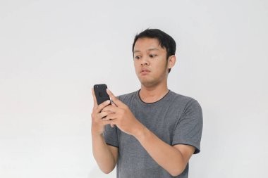 Asyalı adamın, gri arka planda akıllı telefonda gördüklerini görünce şok oldu..