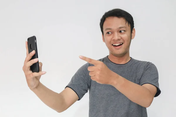 얼굴과 티셔츠를 아시아 청년이 스마트폰으로 놀라는 — 스톡 사진