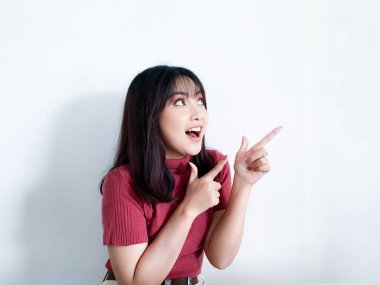 Mutlu ve gülümseyen yüz, kırmızı tişörtlü genç Asyalı kızın gülüşü, boş alanda el işaretli..