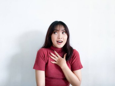 Göğsüne dokunan güzel Asyalı kızın şok olmuş yüzü kırmızı gömlek giyiyor. Reklam modeli konsepti.