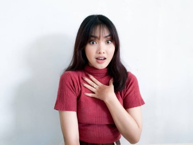 Göğsüne dokunan güzel Asyalı kızın şok olmuş yüzü kırmızı gömlek giyiyor. Reklam modeli konsepti.