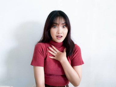 Göğsüne dokunan güzel Asyalı kızın şok olmuş yüzü kırmızı gömlek giyiyor. Reklam modeli konsepti.