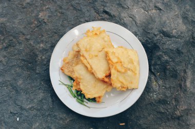 Tempe Mendoan ince tempehten yapılmış, un ile kızartılmış, tadı lezzetli ve soya soslu, beyaz arka planda izole edilmiş soya soslu bir tür tempeh tabağıdır..