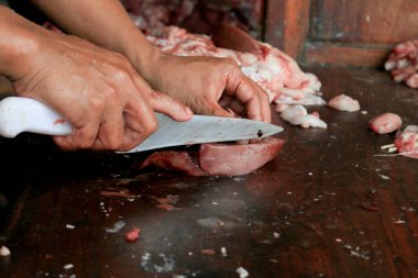 Kasap çiğ ciğer kesiyor ya da bıçakla odun kesme tahtasında inek ve keçi sakatatı kesiyor..