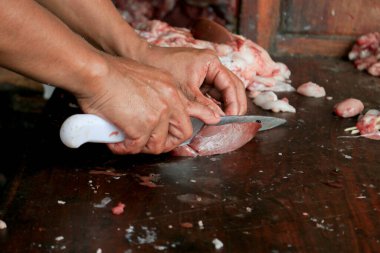 Kasap çiğ ciğer kesiyor ya da bıçakla odun kesme tahtasında inek ve keçi sakatatı kesiyor..