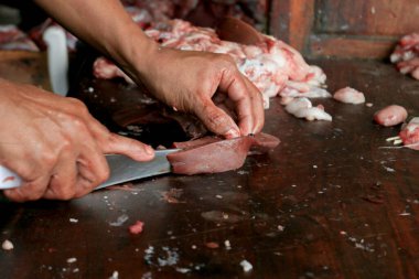 Kasap çiğ ciğer kesiyor ya da bıçakla odun kesme tahtasında inek ve keçi sakatatı kesiyor..