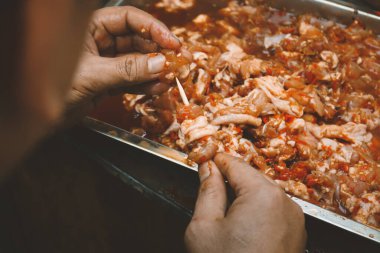 Çiğ tavuk etini bambu çubuğuna koyup satay tavuğu ya da kızartma makinesinde ızgara yapmadan önce kırmızı baharat yapmak.