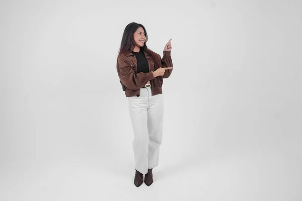 Senyum Gadis Asia Muda Mengenakan Jaket Coklat Berdiri Dan Menunjuk — Stok Foto